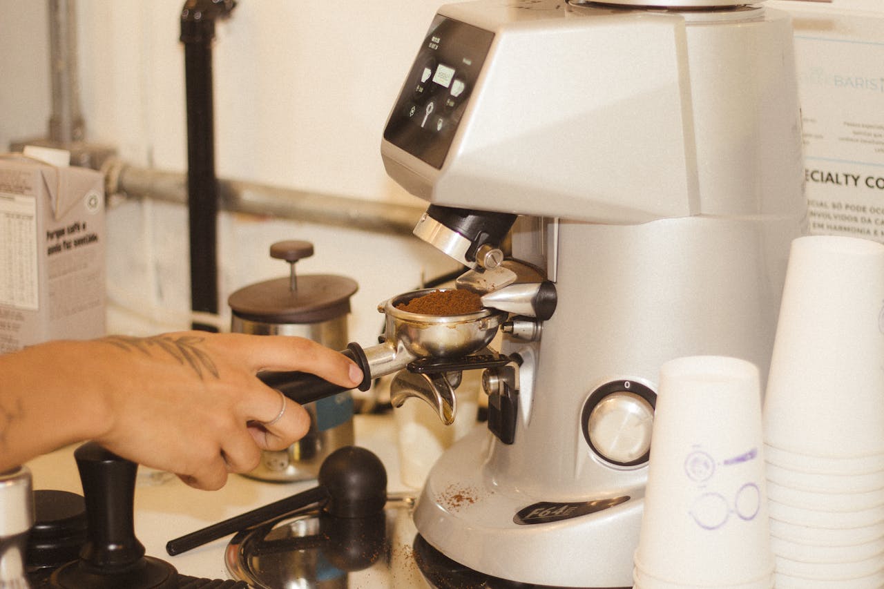 Close-up of a barista using a coffee grinder to prepare fresh espresso.