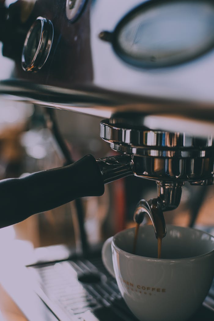 Professional coffee machine in action, brewing espresso into a mug in a cafe setting.